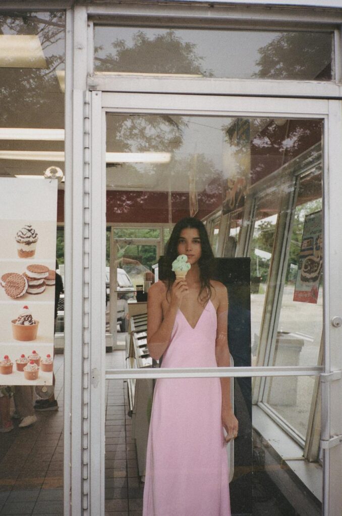 A woman inside a dessert store wearing pink ballet dress.

