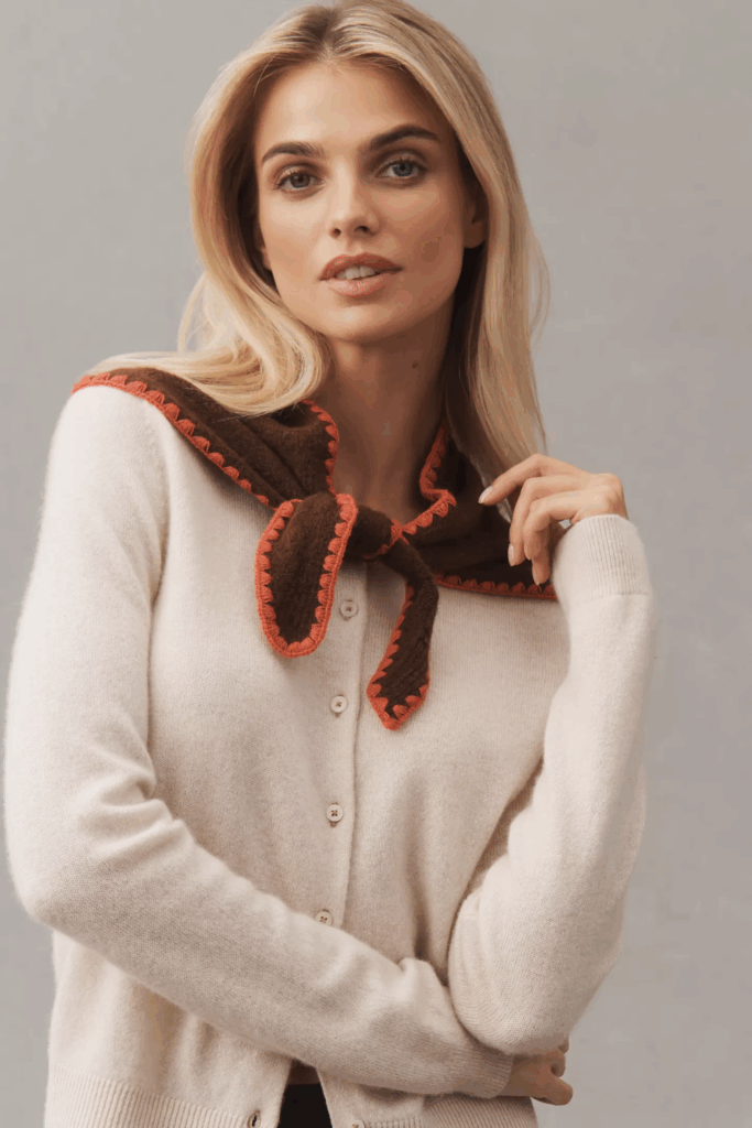 Woman wearing knitted scarf with orange accent.