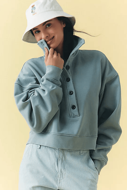Model wearing a  white bucket hat with cute design and light blue funnel neck sweatshirt