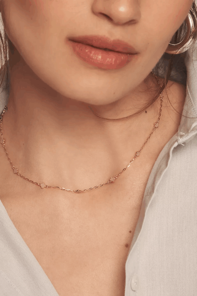 Model wearing necklace with simple clover design.