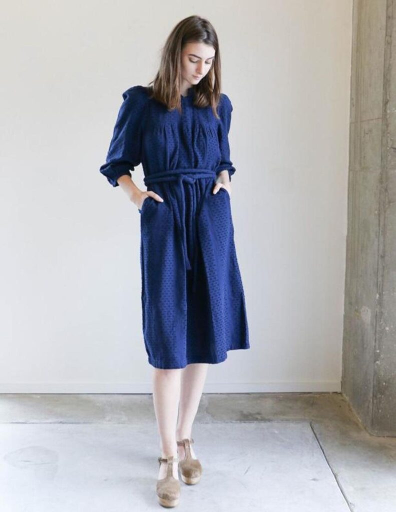 Model wearing lyon blue dress with subtle polka dots pattern. 