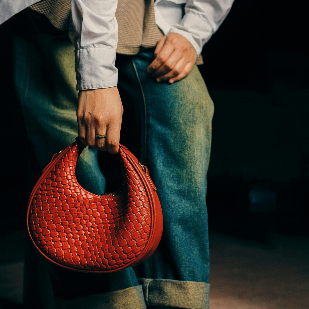 A hand holding a textured bag in warm tones, matching fall fashion trends.