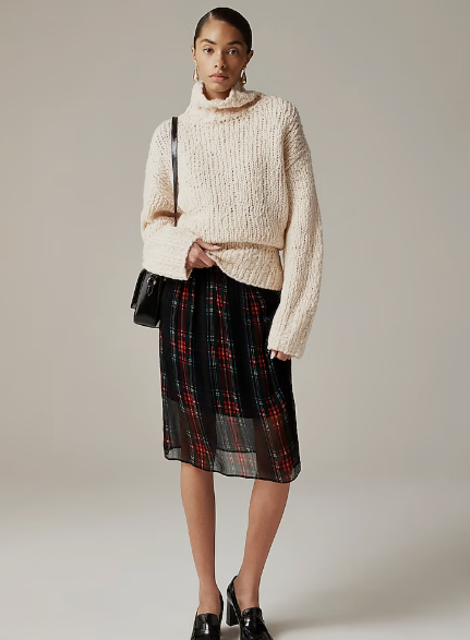 Model wearing white sweater and plaid skirt 