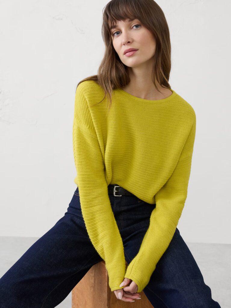 Model seating in a block wearing lemon grass sweater.