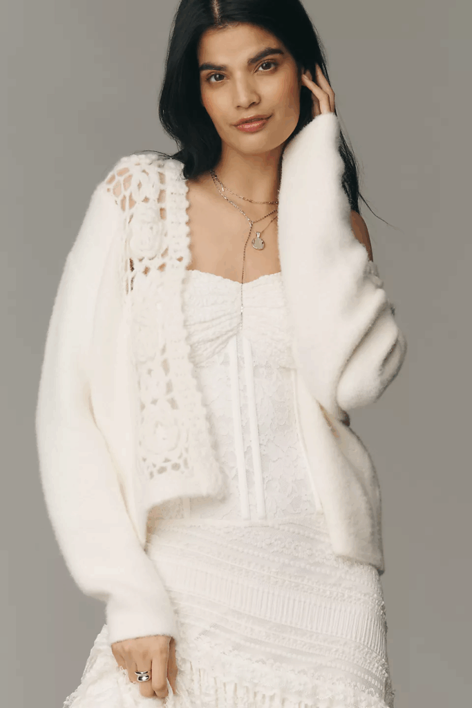 Model wearing white dress and top with white cardigan.