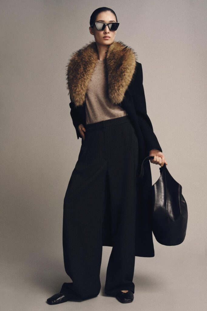 The model looks stylish in her faux fur jacket, which ties the overall black color palette together. 