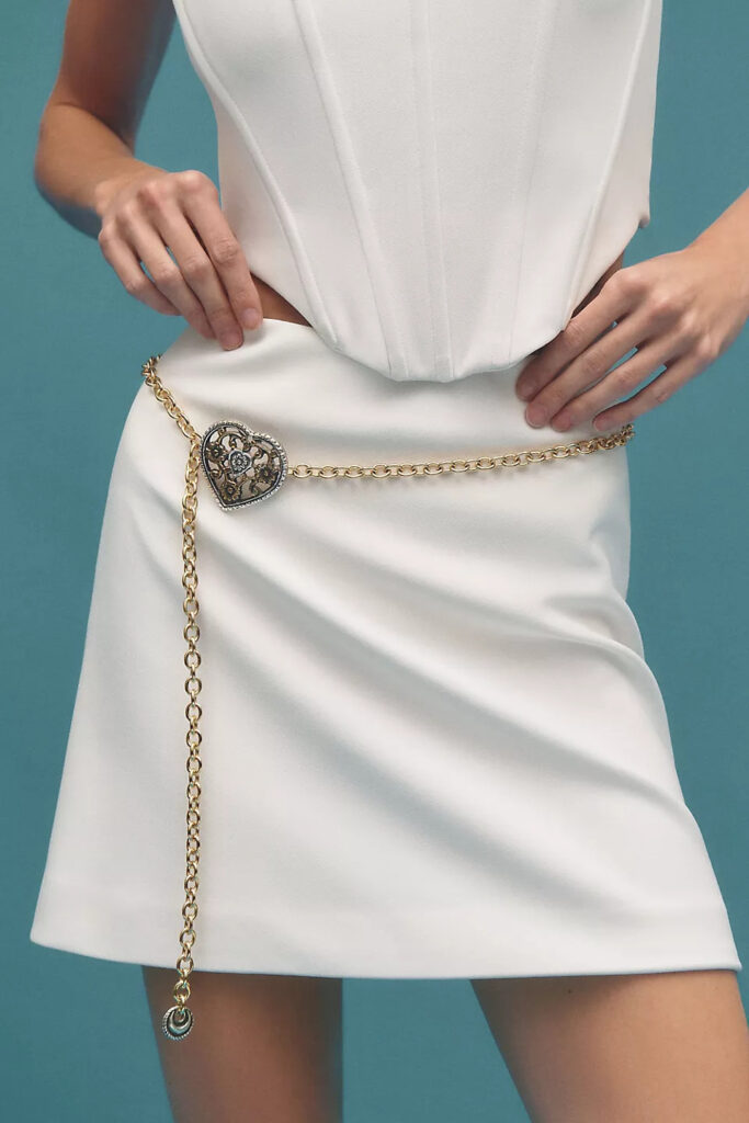 Chain belt with a heart design worn with an all-white outfit.