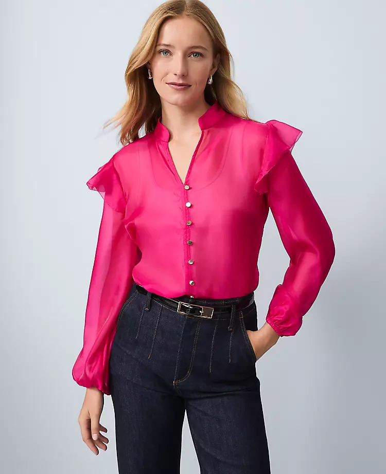 A model styled in a bright pink ruffle blouse with jeans.