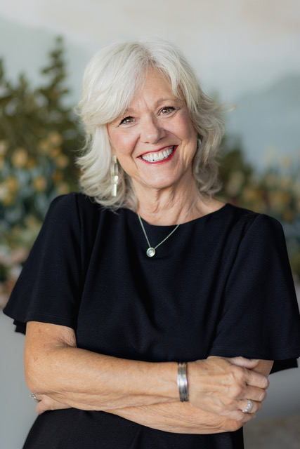 A headshot of a woman smiling wearing black shirt and silver jewelries. 