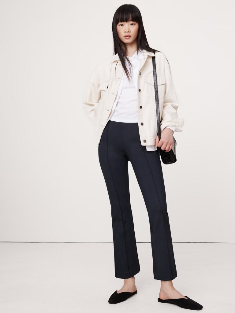 A model styled in a casual look featuring a white shirt, white jacket, and cropped flared pants.
