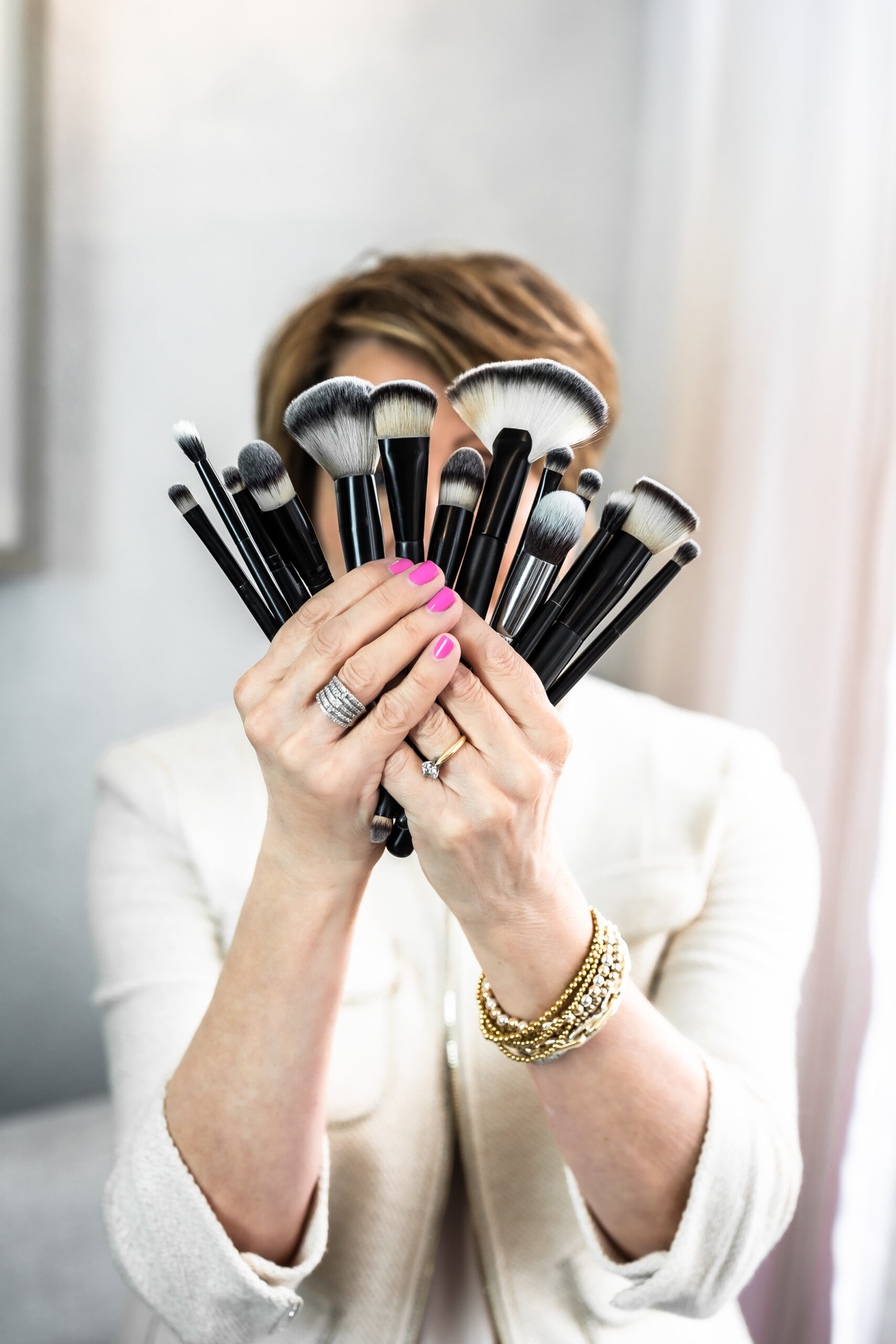 Marla holding makeup brushes up to her face.