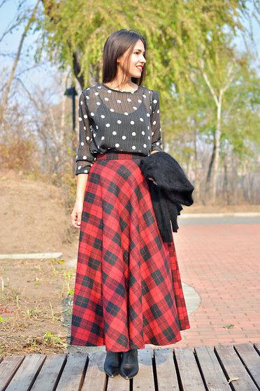 Smiling woman wearing a silk polka dot blouse paired with a heavy plaid skirt.