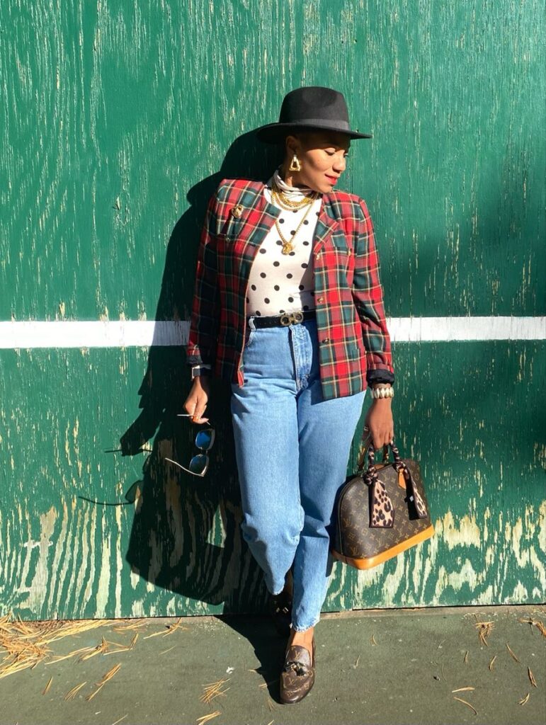 Woman wearing bold plaid blazer layered over a small polka dot blouse for a casual look.