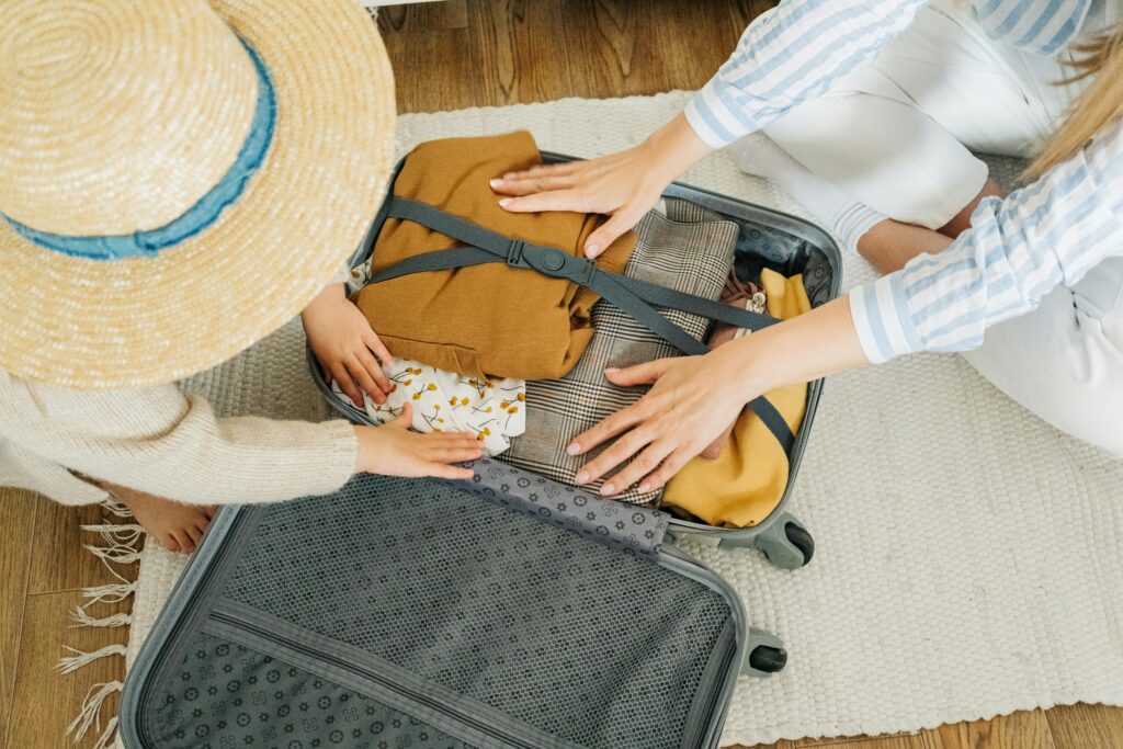 A woman and her child packing items into a carry-on suitcase.