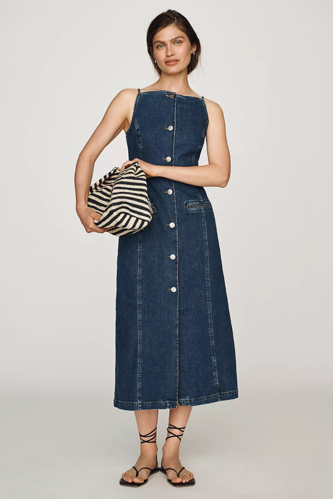 Denim dress paired with a striped bag and casual sandals for a polished summer event outfit.