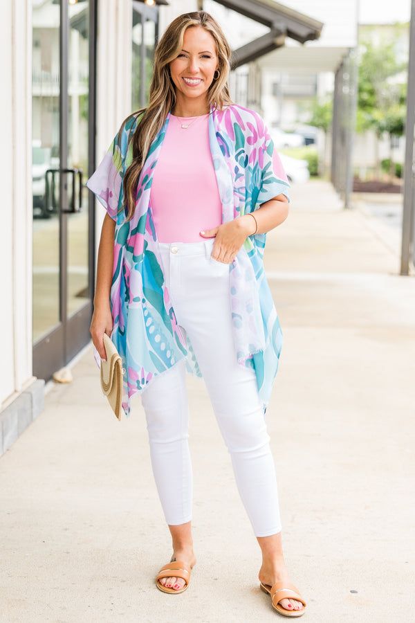 Lightweight colorful kimono styled with a bright pink top and white pants for a playful summer look.