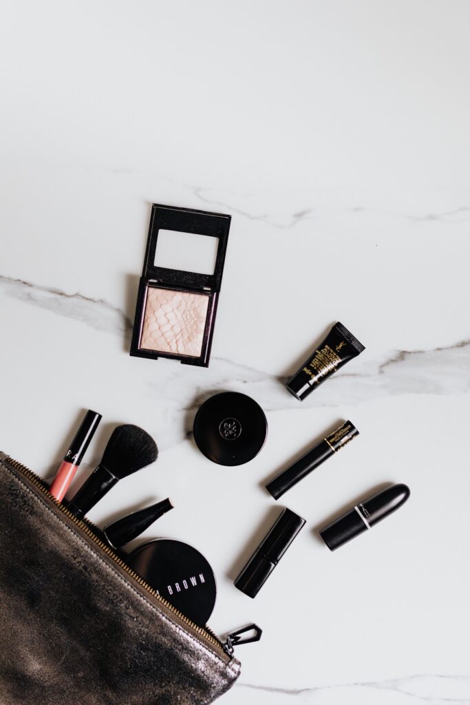 Summer makeup bag with its beauty essentials neatly laid out on a table.