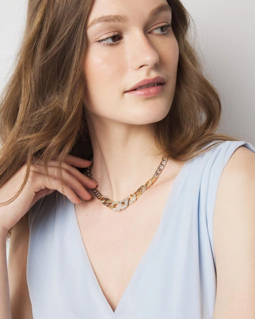 Close-up of a model wearing a layered gold necklace.