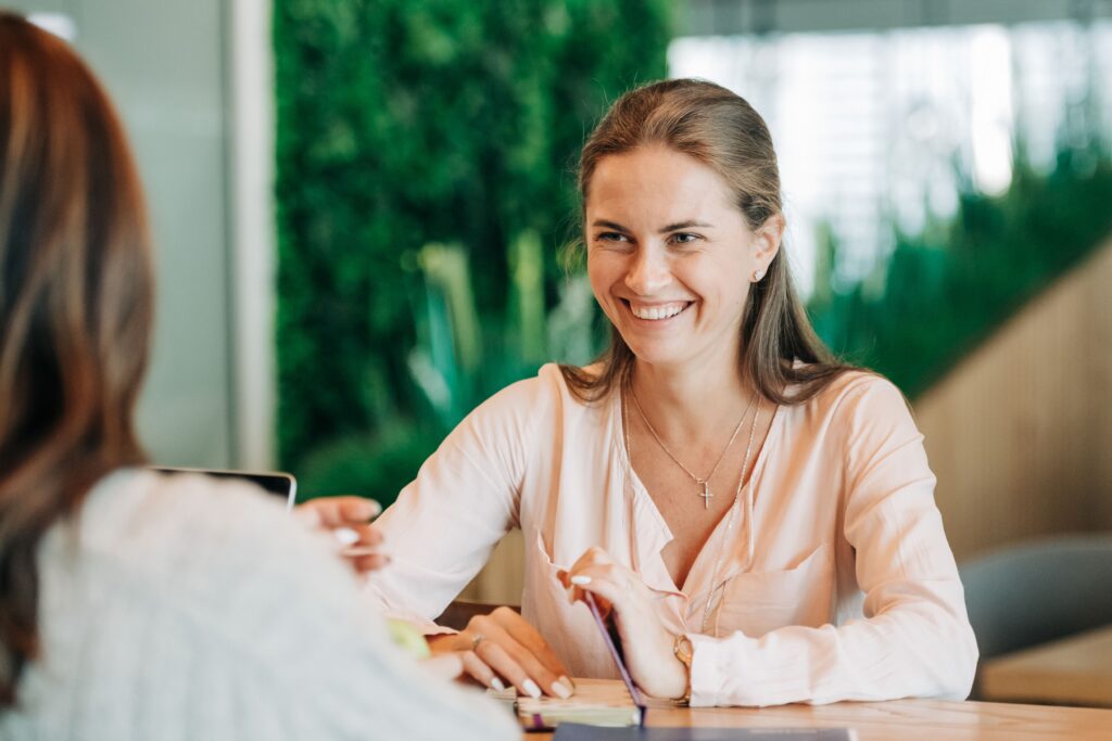 Woman smiling while talking with another person.