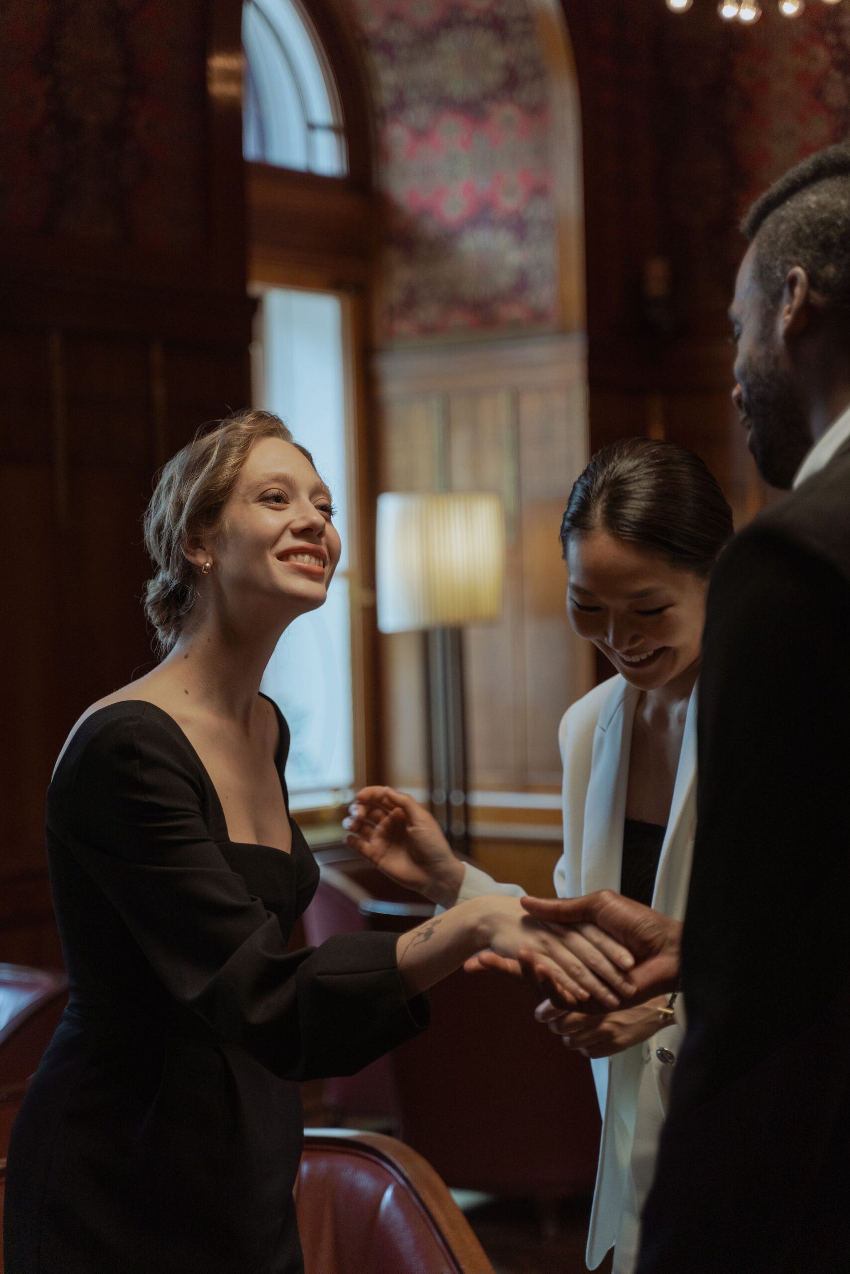 Woman smiling while speaking with guests at an event.