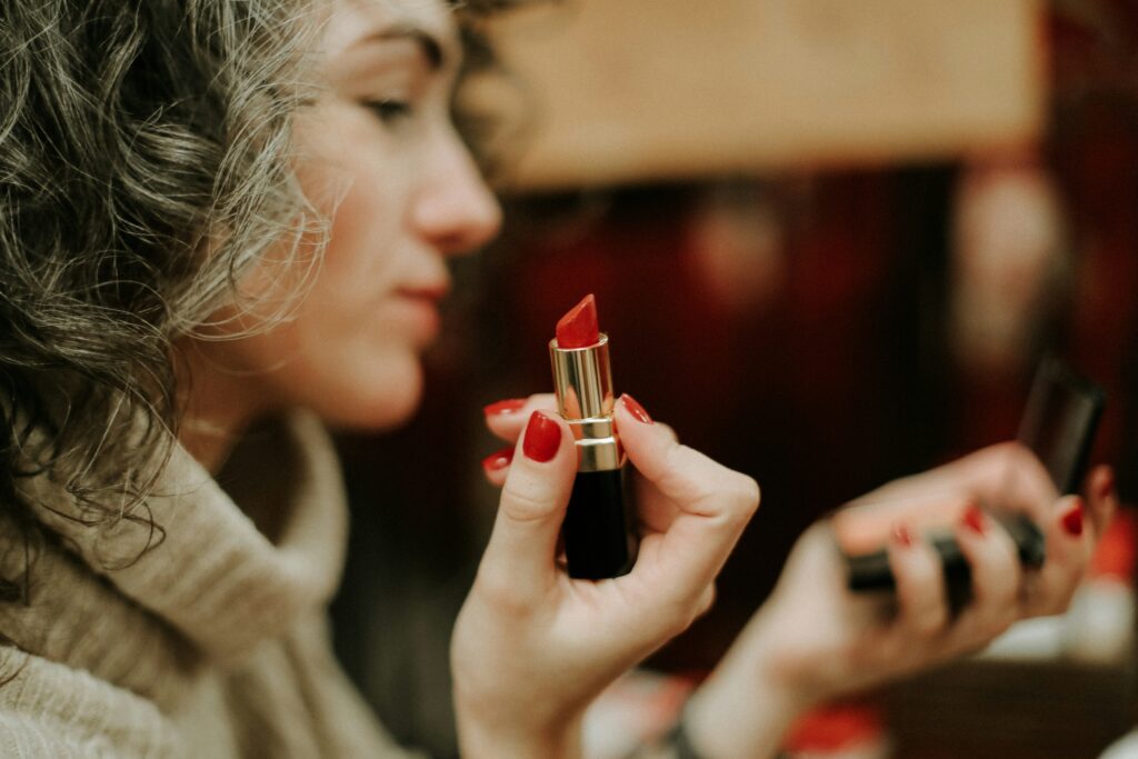 Woman holding a red lipstick near her face.