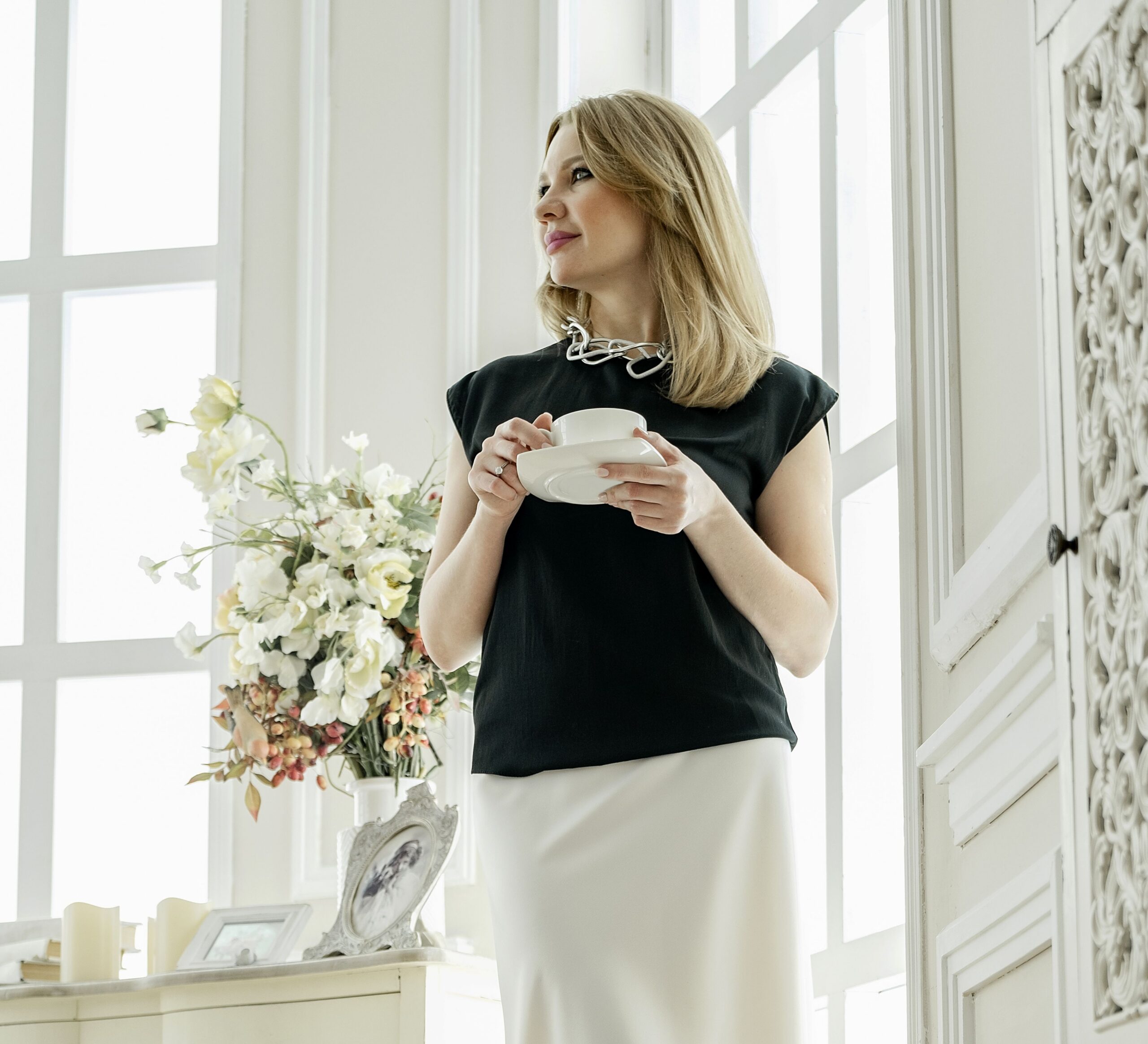 Elegantly dressed woman standing while holding a cup