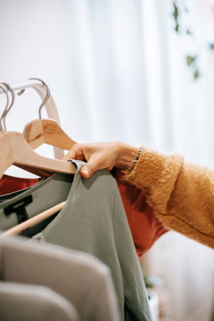 A close-up of a person browsing clothes on a clothing rack.